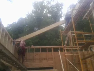 Carpenter raising a rafter beam on a new second story frame in Bethlehem